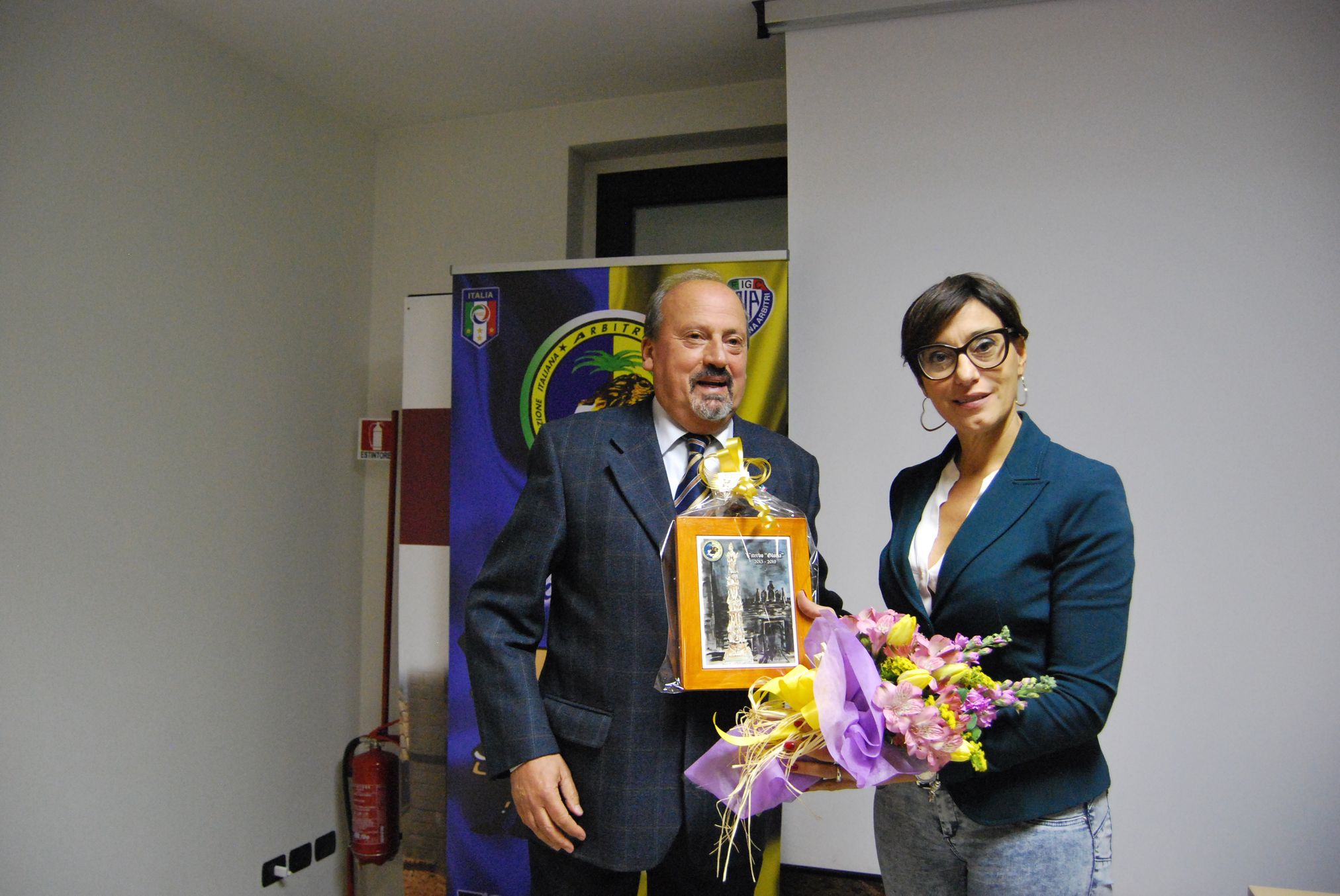 da sinistra Luigi Gasbarri consegna fiori e un oggetto ricordo a Silvia Tea Spinelli